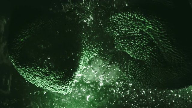 A professional dry microfiber rag for washing a car is dipped in water. Bottom view from under the water. Underwater view of towel in hand in black glove. The tissue in fluid air bubbles and flows.