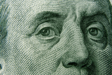 Closeup on Benjamin Franklin eyes from 100 dollar bill. American currency as a world money concept.