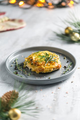 Baked pork with cheese and thyme in a gray plate on a gray background in the new year's serving.