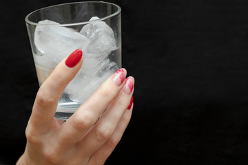 Ice cubes in the hand. Black background. A glass of water. Cold. Frozen. White.