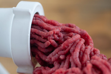 Cook makes minced fresh meat in a meat grinder