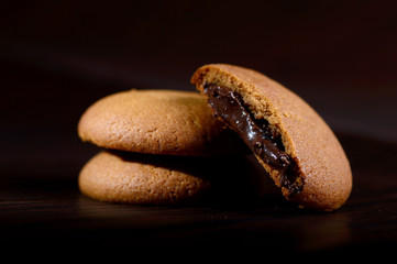 Biscuits filled with chocolate cream. Chocolate cream cookies. brown chocolate biscuits with cream filling on black background.