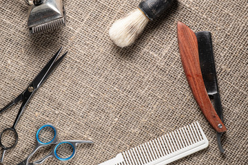 vintage barber tools dangerous razor hairdressing scissors old manual clipper comb shaving brush. on sackcloth background.