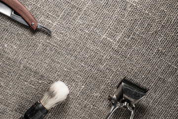 vintage barber tools dangerous razor hairdressing scissors old manual clipper comb shaving brush. on sackcloth background.