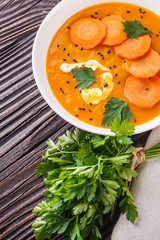 pumpkin carrot cream soup on rustic wooden background