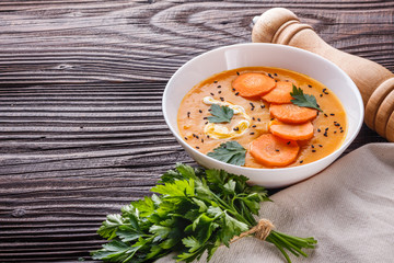 pumpkin carrot cream soup on rustic wooden background