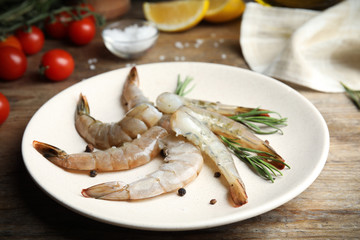 Fresh raw shrimps with rosemary and pepper on wooden table