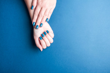 Beautiful women's hands with a neat blue manicure.