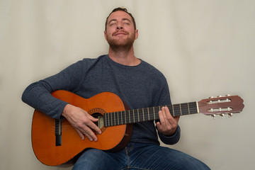 Obraz premium Happy man enjoying while is playing the spanish guitar.