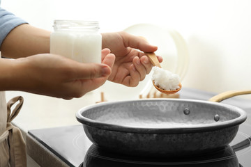 Woman cooking with coconut oil on induction stove, closeup