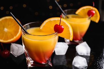 Fresh alcoholic Tequila Sunrise cocktail on black table
