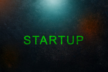 startup inscription on a dark industrial background with metal texture and light spots