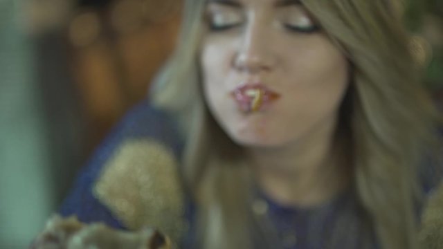 Angry greedy attractive blonde young woman biting huge pieces of meat eating with hands inappropriate in close up shot