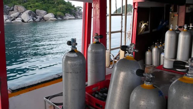 Row of oxygen tanks and diving equipment placed on modern boat in rippling ocean near Koh Tao resort, Thailand. Concept of tourist sports extreme entertainment, adventure and new experience