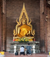 Obraz premium Buddhist faithful pray inside Wat Yai Chai Mongkhon, a Buddhist temple of archaeological park, Ayutthaya, Thailand