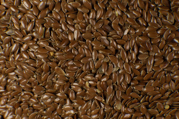 Linum usitatissimum is scientific name of Brown Flax seed. Also known as Linseed, Flaxseed and Common Flax. Closeup of grains, background.