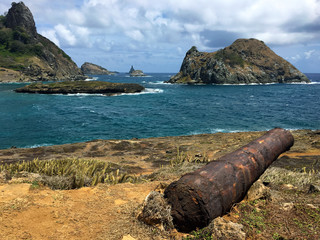Old rusted cannon overlooking Sueste Bay seen from São Joaquim Fort in Fernando de Noronha, Brazil