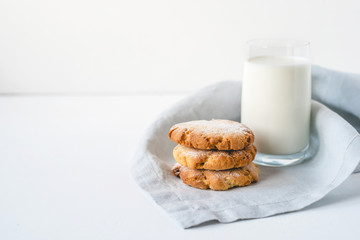 Stacked cookies on a linen napkin and a glass of milk.