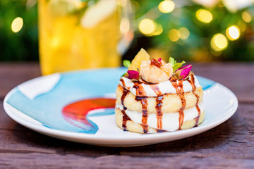 Cottage cheese pancakes or syrniki with cream, fruit jam and flower decoration