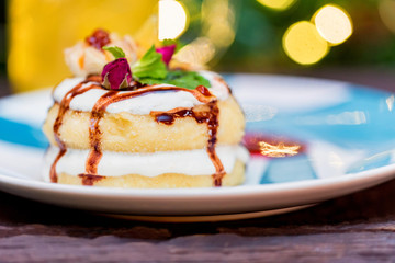 Cottage cheese pancakes or syrniki with cream, fruit jam and flower decoration