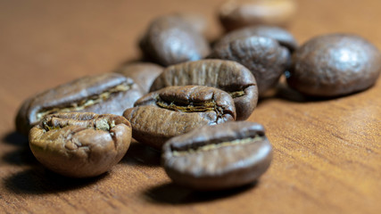 Fresh fragrant coffee grains close-up on a wooden table. Macro photography.