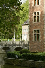 Un coin du château avec l'une de ses dépendances et le pont en pierres sous la nature luxuriante du domaine Coloma à Sint-Pieter-Leeuw