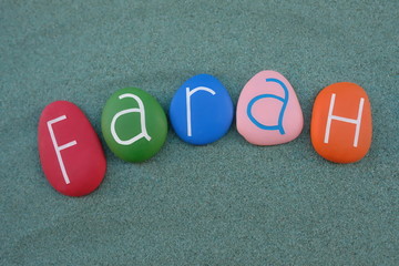 Farah, female given name composed with multi colored stone letters over green sand