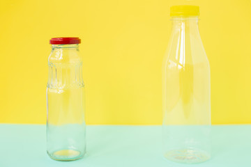 Glass bottle for drinks with a red cap and a plastic bottle on a yellow-blue background. An example of packaging that is healthy and environmentally friendly and then properly recycled and disposed of