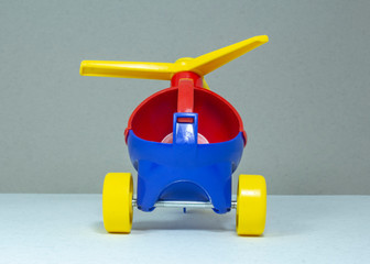 Children's toy, plastic red-blue helicopter with a yellow propeller and wheels on a gray fleecy...