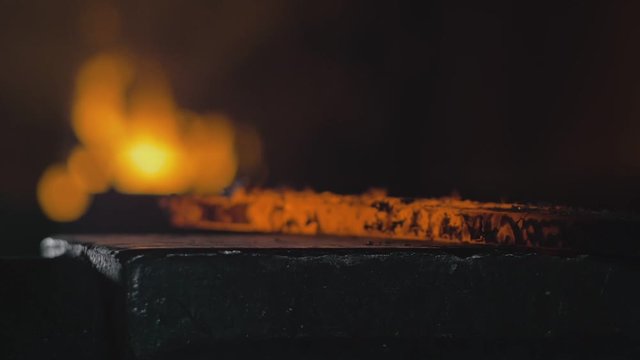 Forge workshop. Smithy manual production. Hands of smith with hammer hit on glowing hot metal, on the anvil, the forging process. Blacksmith makes iron products for manufacture of fireplace, stove.