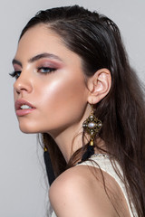 Portrait of a very beautiful girl with professional makeup, ideal skin, rose eyeshadows and lips and long earrings