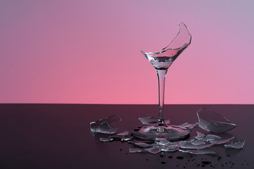 broken wineglass on the table with colored background
