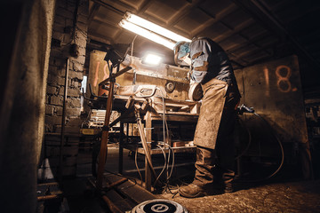 Busy man is working at his workplace at the metal factory.