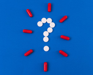 question mark laid out of white tablets on a blue background
