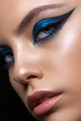 Close up portrait of a beautiful girl with professional makeup, ideal skin, bright blue graphic smokey eyes