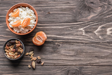 Obraz na płótnie Canvas A set of products for a healthy balanced breakfast. Tangerines, nuts and cottage cheese, rich in vitamins and calcium on a wooden background. The concept of natural organic products in season.
