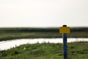 gelbes schild mit freifeld vor wiese und horizont