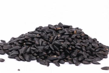 Pile of black sunflower seeds.  Roasted seeds on white background. Shallow depth of field
