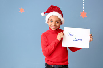 Cute African-American boy with letter to Santa Claus on color background