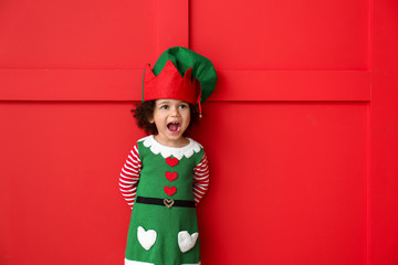 Little girl in costume of elf on color background