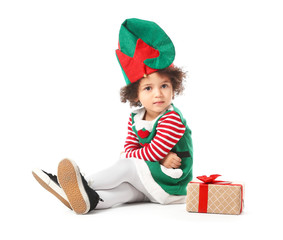 Little girl in costume of elf and with Christmas gift on white background