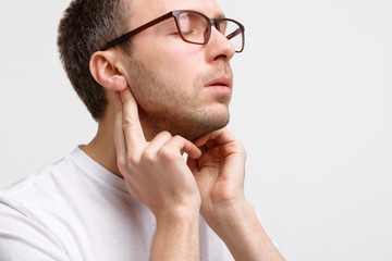 Fototapeta premium Close up portrait of sick man touches the lymph glands with his fingers near the ear, suffering from pain, closed eyes, isolated. Lymphadenitis, immunity weakened after illness, otitis. 