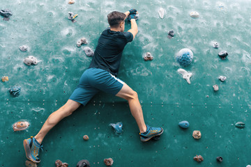 A man climbing in boulder gym in the wall.