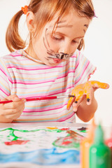 Carnival makeup. Lttle beautiful child girl painting with colour hands and face.
