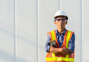 Thai handsome man engineer standing with a meter in front of the container.