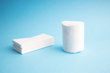 Hygiene discs and napkins. White hygiene napkins on a blue background. Skincare mockup for design. Stack of disposable napkins. Cosmetology concept.