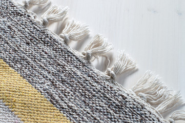 Folded cotton doormat close up with diagonal yellow and black stripes and decorative fringe