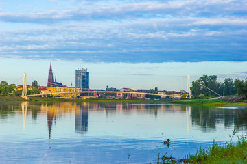 Fototapeta na wymiar Osijek / Croatia: 10th May 2019: Cityscape of Osijek in sunrise - cathedral, pedestrian bridge and river Drava