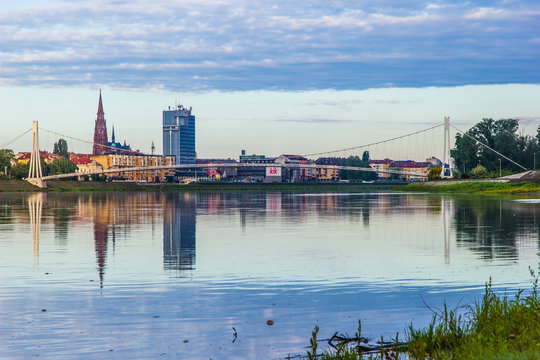 Osijek / Croatia: 10th May 2019: Cityscape of Osijek in sunrise - cathedral, pedestrian bridge and river Drava