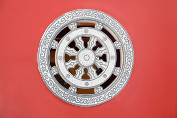 Stone rosette relief - window made of decorated stone relief, ornaments and relief on the red wall from Chinese buddhism temple, Fujian,China.